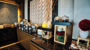 A modern kitchen with a marble countertop, a hexagonal patterned wall, and various food items and decorations.