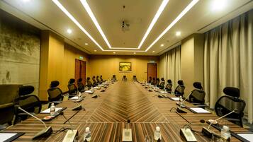A conference room with a long table, chairs, microphones, and water bottles.