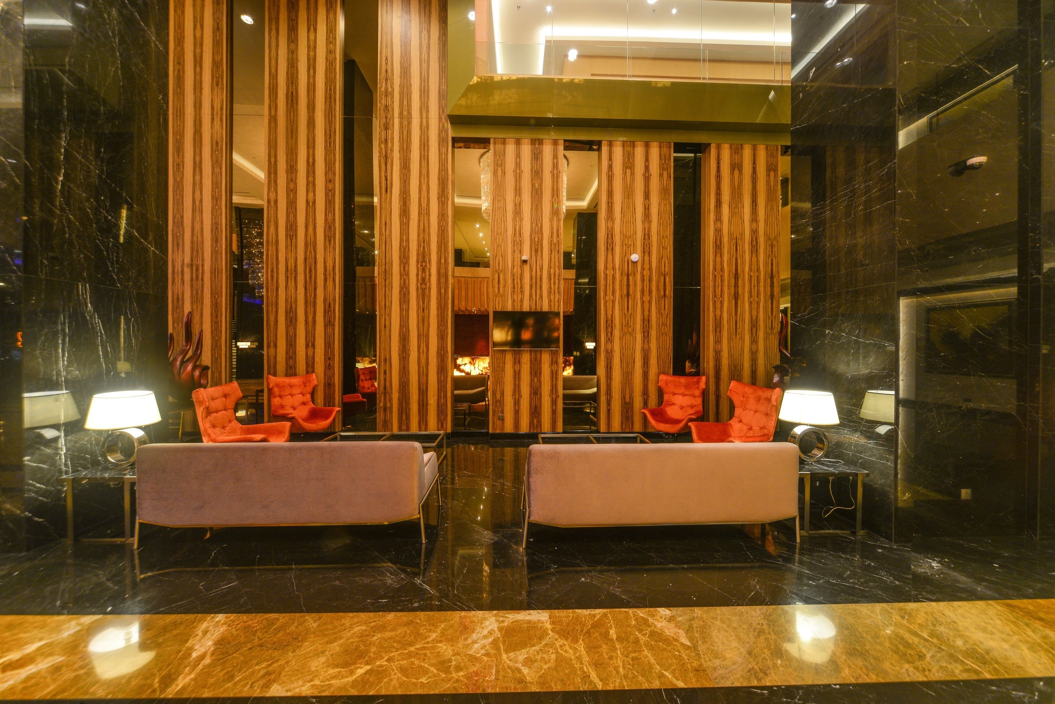 A lobby with a reception desk, two armchairs, a sofa, and a large mirror.