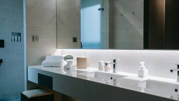 A modern bathroom with a large mirror, a white sink, and a towel rack.