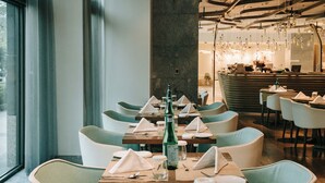 A restaurant with tables set for dining, featuring a modern interior with hanging light fixtures and a bar area in the background. - Hotel Royal Beitou (Taipei)