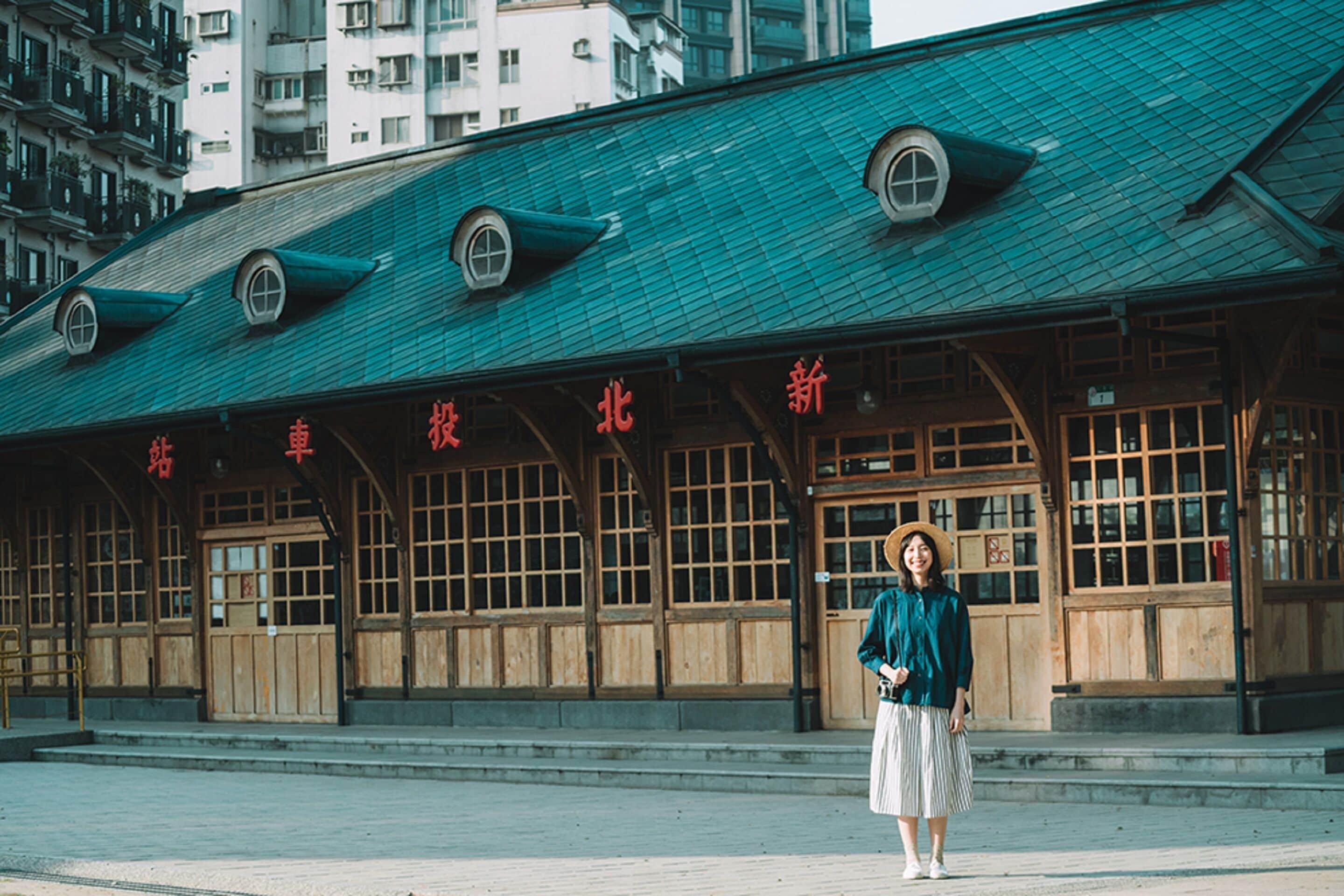 A traditional building with a green roof and wooden facade, featuring large windows and a sign with Chinese characters.