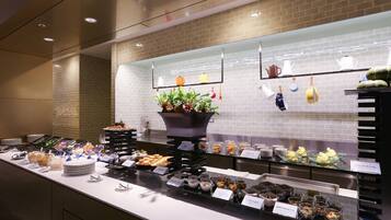 Un buffet proposant une variété de plats et agrémenté d’une composition florale en guise de décoration centrale.