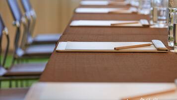 A meeting room with a long table, chairs, water bottles, and a notebook.
