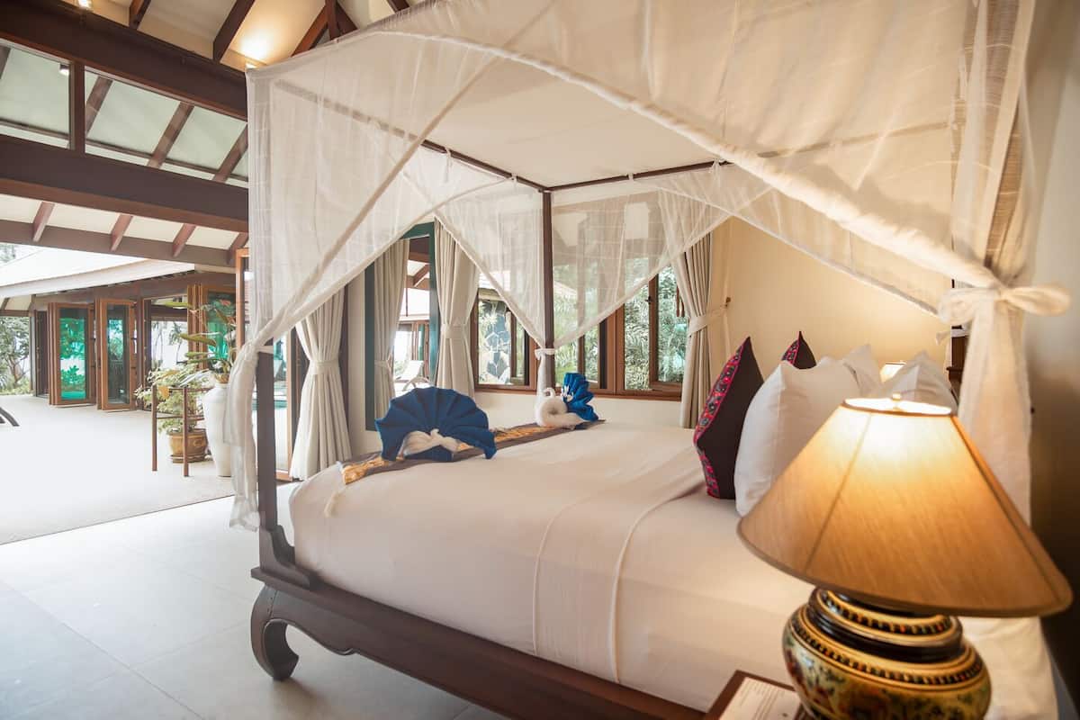 Une chambre spacieuse avec un grand lit, un baldaquin et une vue sur l’extérieur.