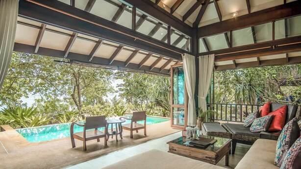 A spacious outdoor seating area with a pool, wooden furniture, and a view of lush greenery. - Koh Jum Beach Villas “A member of Secret Retreats” (Nuea Khlong)