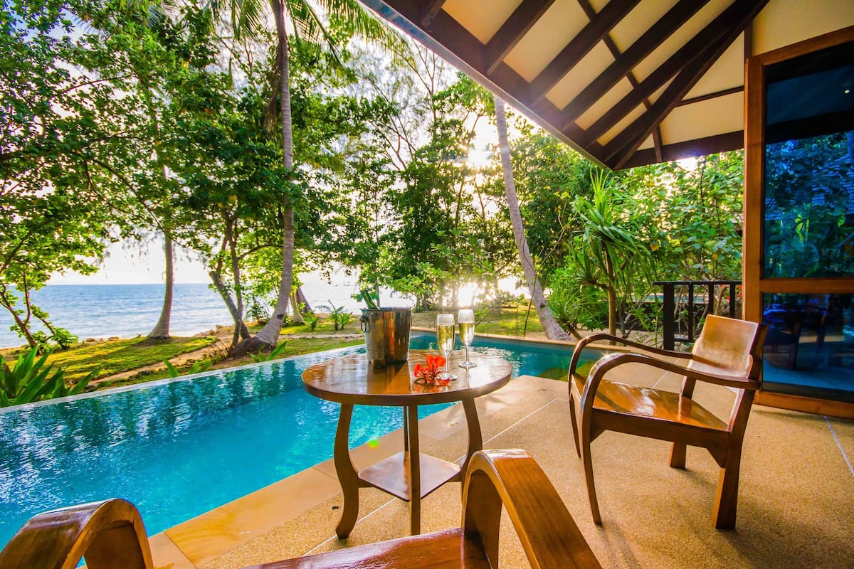 Un espace aménagé au bord de la piscine, avec une table et des chaises, une vue sur la mer et une végétation luxuriante.