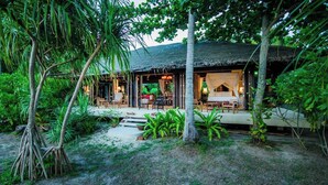 A thatched-roof bungalow with outdoor seating and a garden. - Koh Jum Beach Villas “A member of Secret Retreats” (Nuea Khlong)