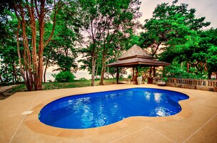 Una piscina al aire libre, sillones reclinables de piscina