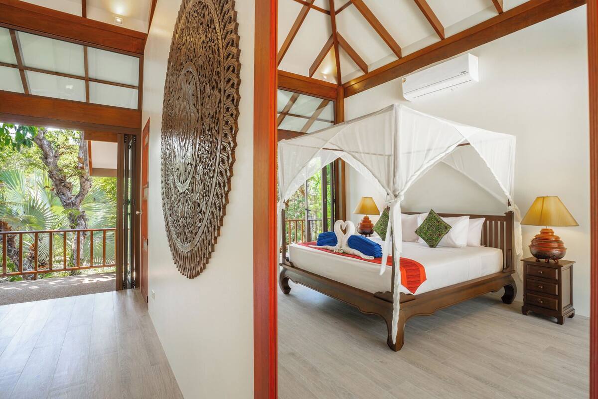 Une chambre à coucher avec un lit à baldaquin, un élément décoratif mural et une vue sur l’extérieur.