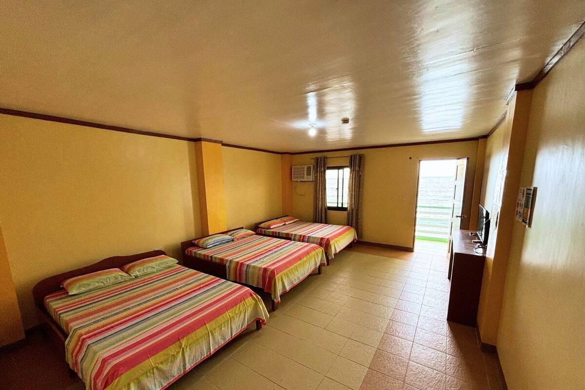 Une chambre d’hôtel avec quatre lits, un bureau et une fenêtre avec des rideaux.