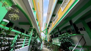 A multi-level atrium with green and white walls, multiple balconies, and potted plants. - White Beach Hotel Puerto Galera powered by Cocotel (Puerto Galera)