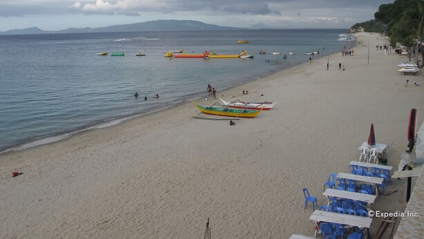 A beach with boats, a sandy shore, and a few people. - White Beach Hotel Puerto Galera powered by Cocotel (Puerto Galera)