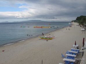 Une plage avec des bateaux, un rivage sablonneux et quelques personnes.