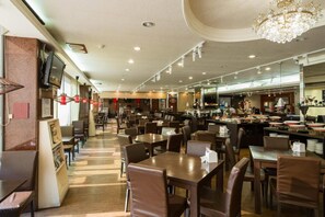 A spacious restaurant with multiple dining areas, a bar, and a kitchen visible in the background.