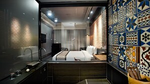 Una habitación de hotel moderna con una cama grande, un baño con bañera y una pared decorada con azulejos.