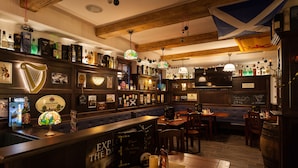 A bar area with wooden beams, a variety of liquor bottles, and a harp decoration. - Vitusfort (Fuessen)