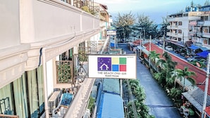 Un hôtel avec une enseigne indiquant « The Beach Cha-Am Guest House » et une vue sur la rue en contrebas.