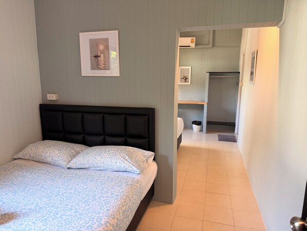 Une chambre avec un lit, un tableau encadré au mur et un couloir menant à une salle de bain.