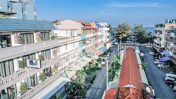 Un edificio de varios pisos con balcones, una calle al frente y coches estacionados.