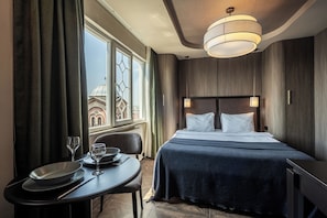 Een hotelkamer met een bed, nachtkastje en uitzicht op een gebouw.
