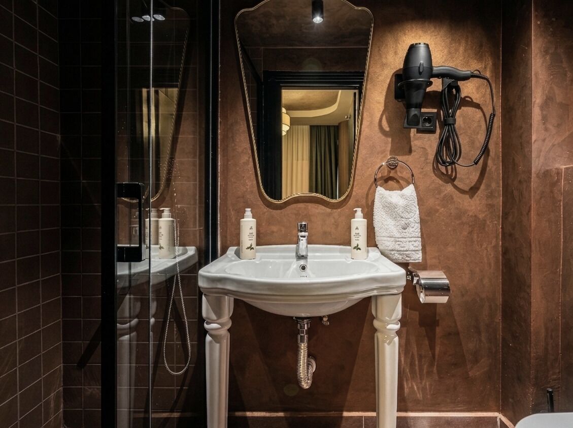 Ein Badezimmer mit einem weißen Waschbecken, einem Spiegel, einem Haartrockner und einem Handtuchhalter.