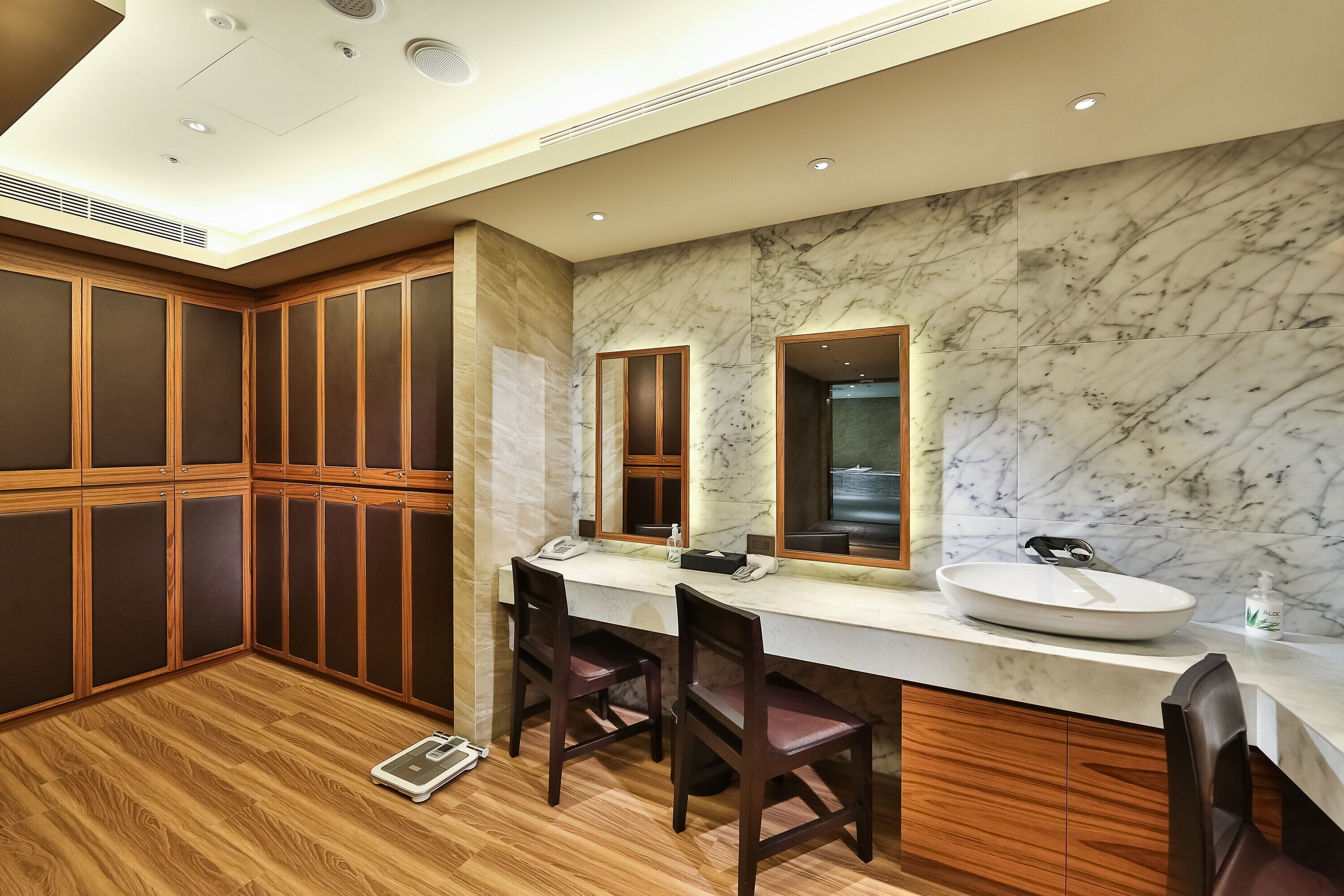 A modern bathroom with a wooden vanity, marble backsplash, and a large mirror.