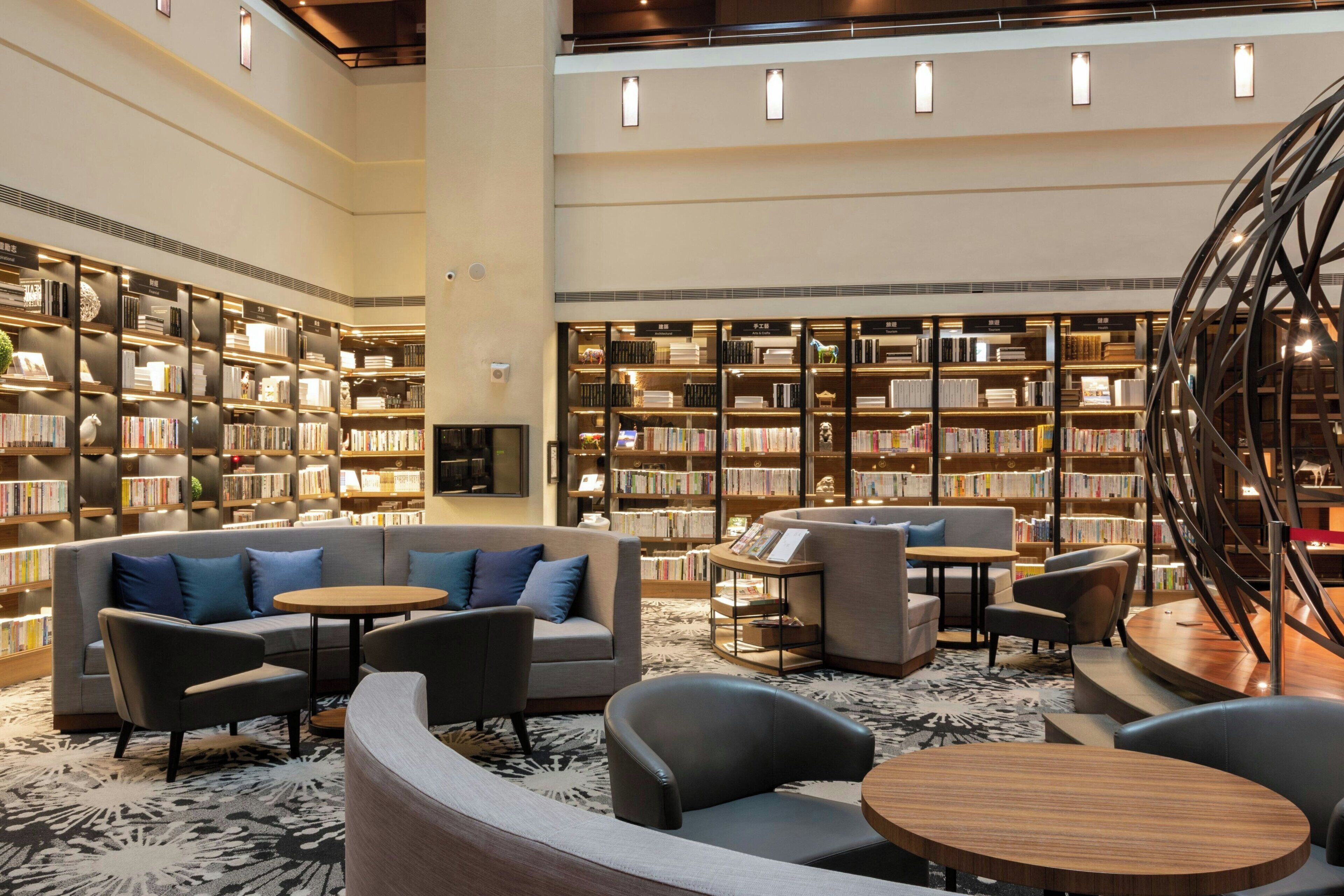 Eine großzügige Bibliothek mit verschiedenen Sitzbereichen, darunter Sofas und Sessel, umgeben von hohen Bücherregalen.