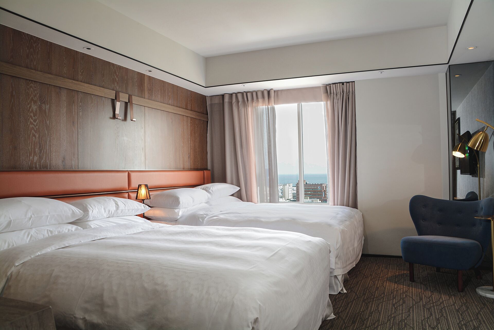 Hotelkamer met een groot bed, een zithoek met een stoel en uitzicht op de stad.