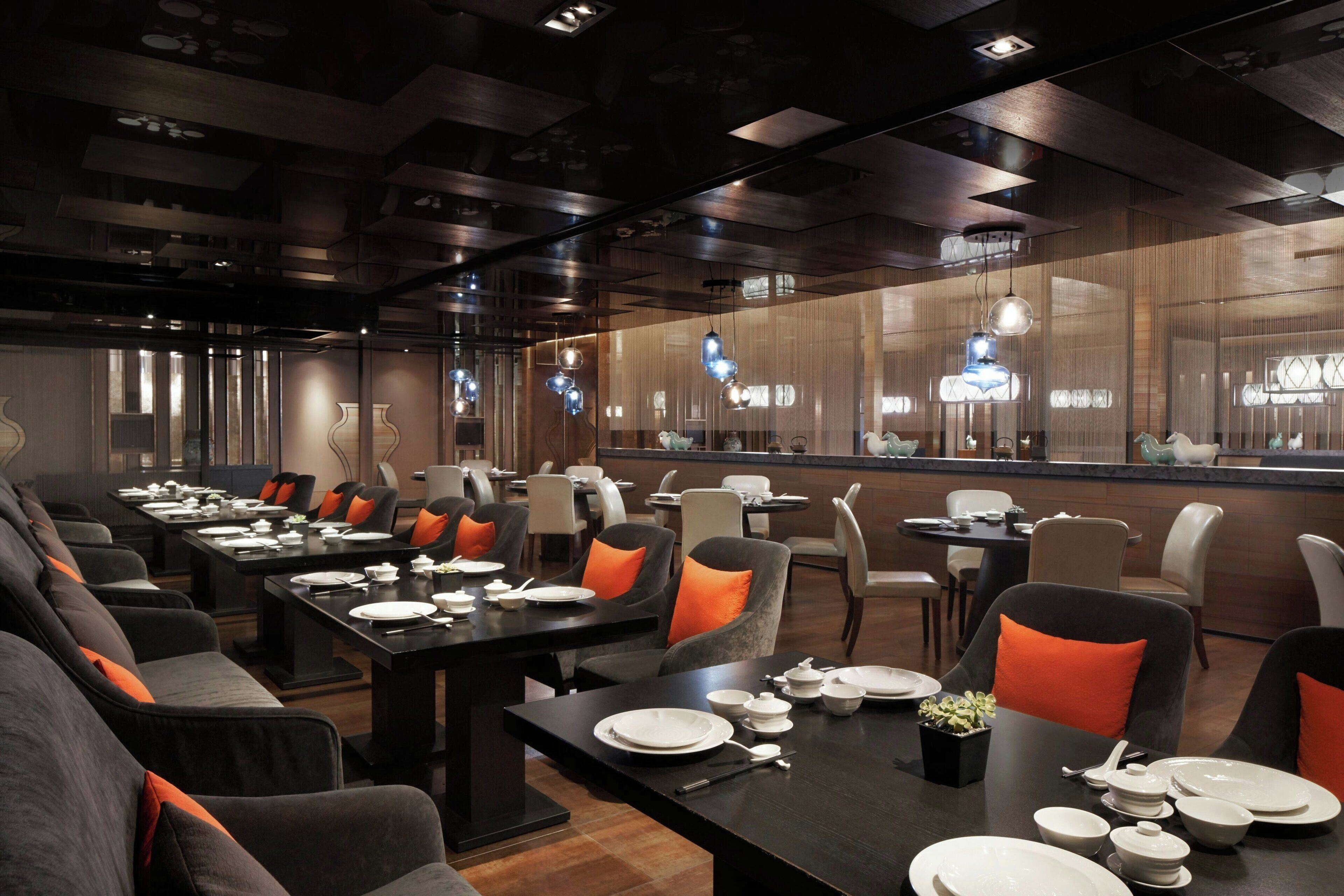 A modern restaurant with long tables and comfortable seating.