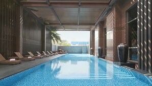 Una piscina con sillas de descanso y piso de baldosas.