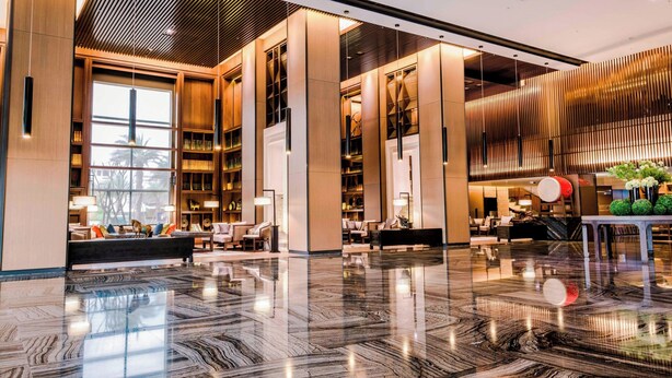 Un vestíbulo amplio con piso de mármol pulido, ventanas grandes y un diseño interior moderno.