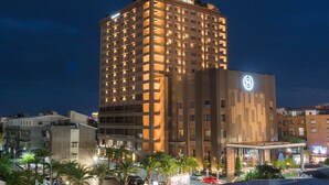 Un hotel de varios pisos con un diseño moderno, que destaca por un logotipo circular en la fachada.