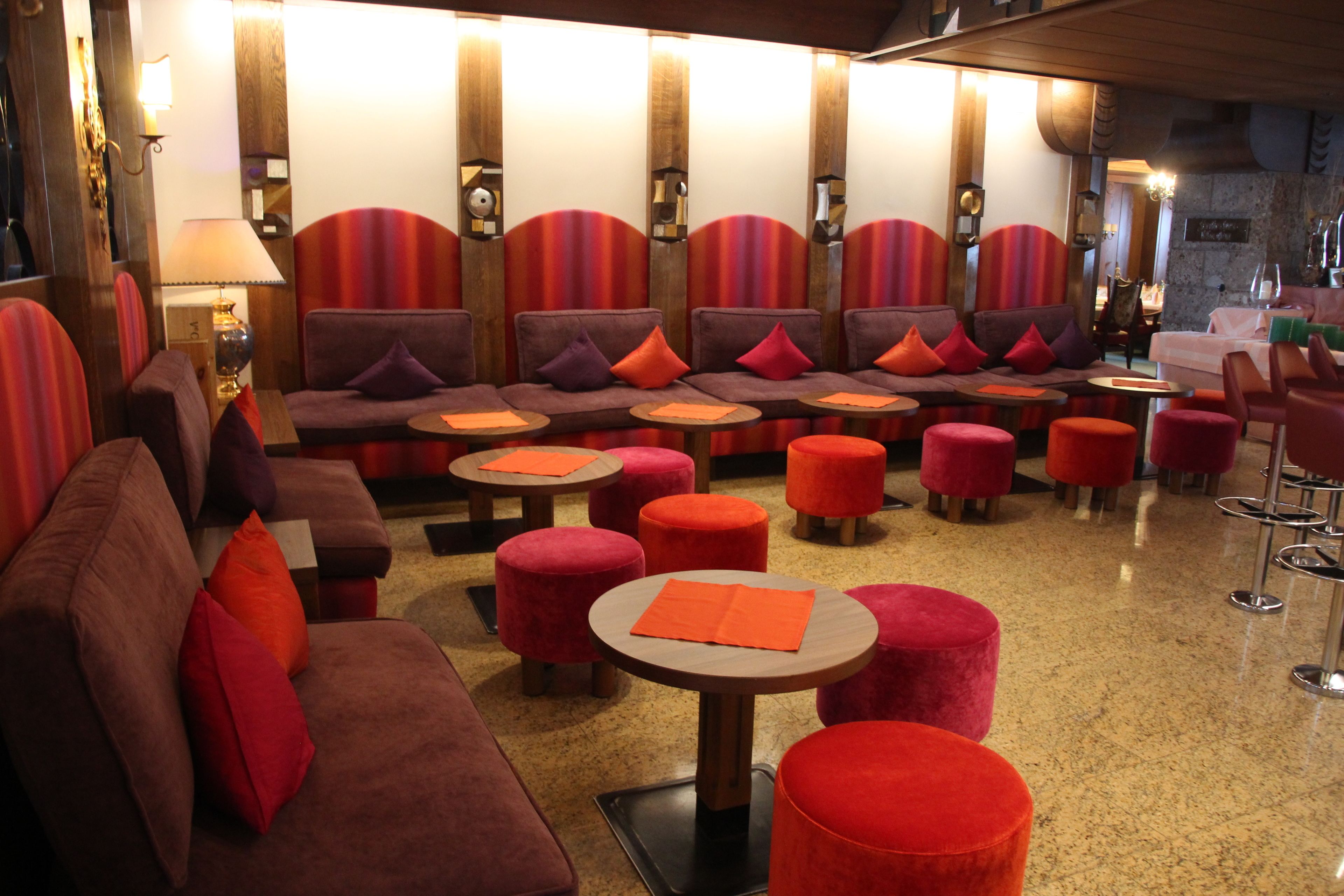 A seating area with sofas and ottomans, a table, and a bar area with stools.