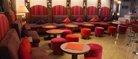 A seating area with sofas and ottomans, a table, and a bar area with stools.