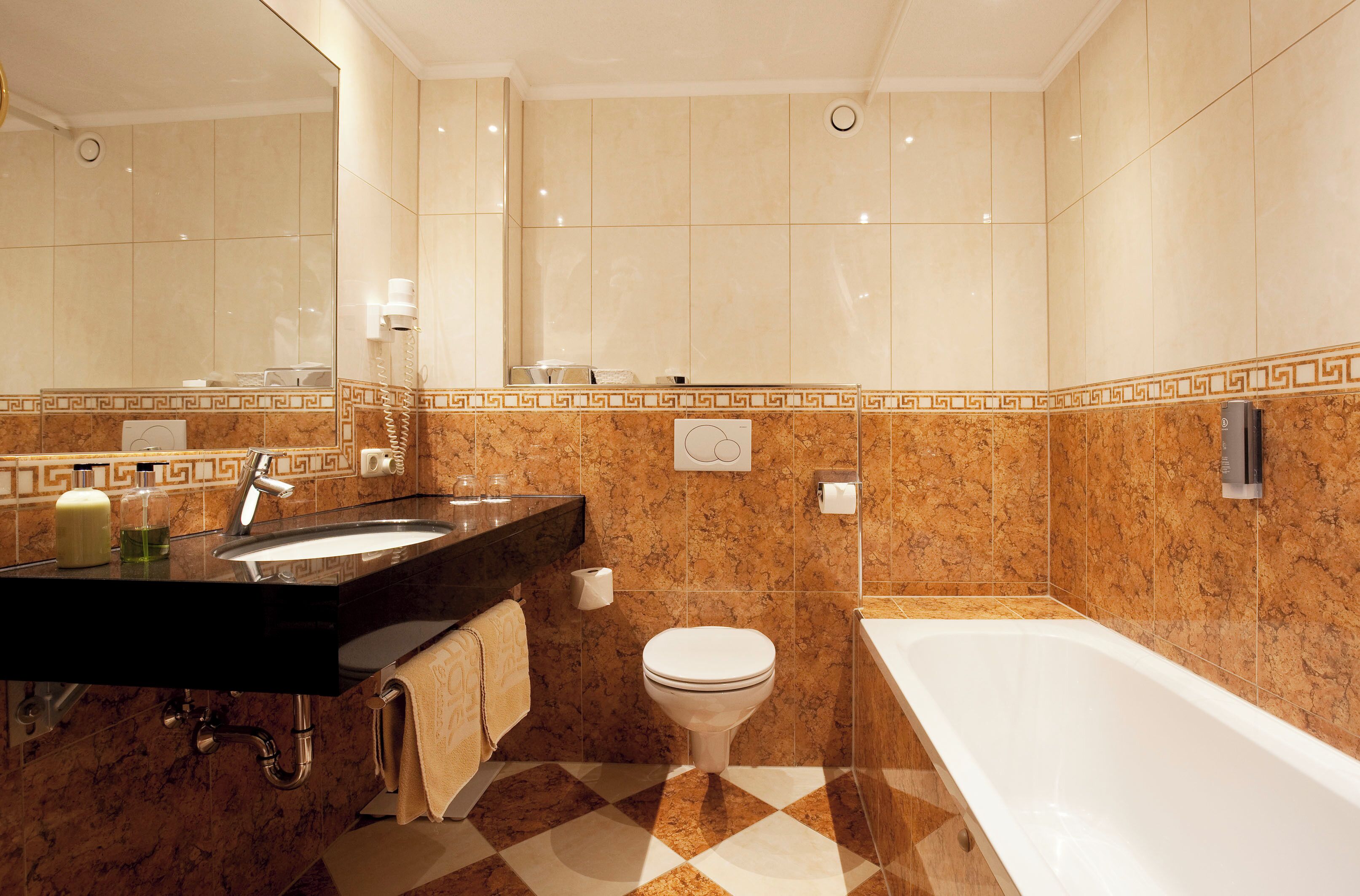 Un baño moderno con tocador de mármol, inodoro y bañera.