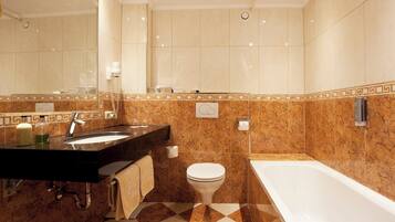 A modern bathroom with a marble vanity, a toilet, and a bathtub.