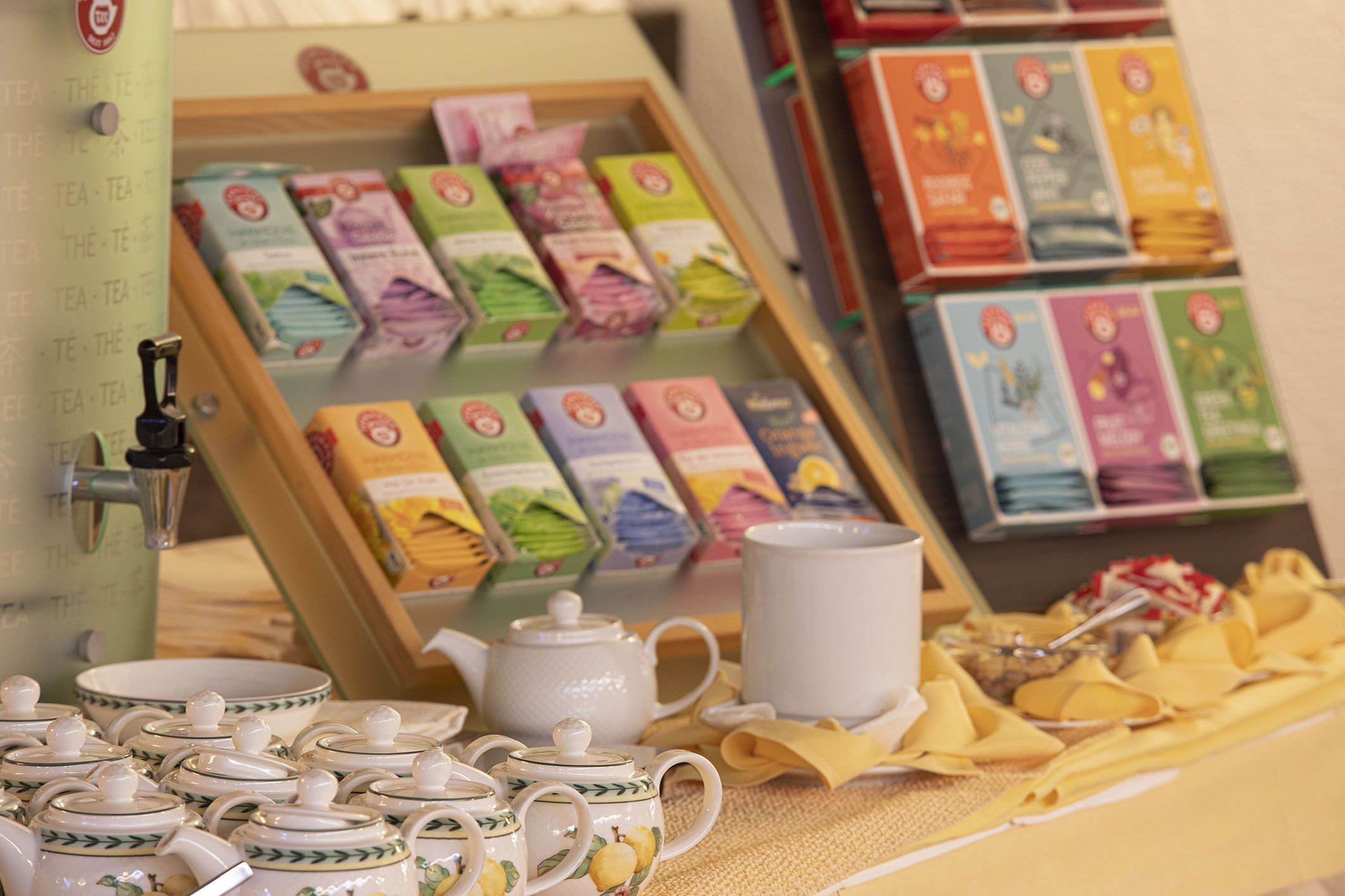 Una exhibición de tés con diferentes cajas de té y una tetera sobre una mesa.