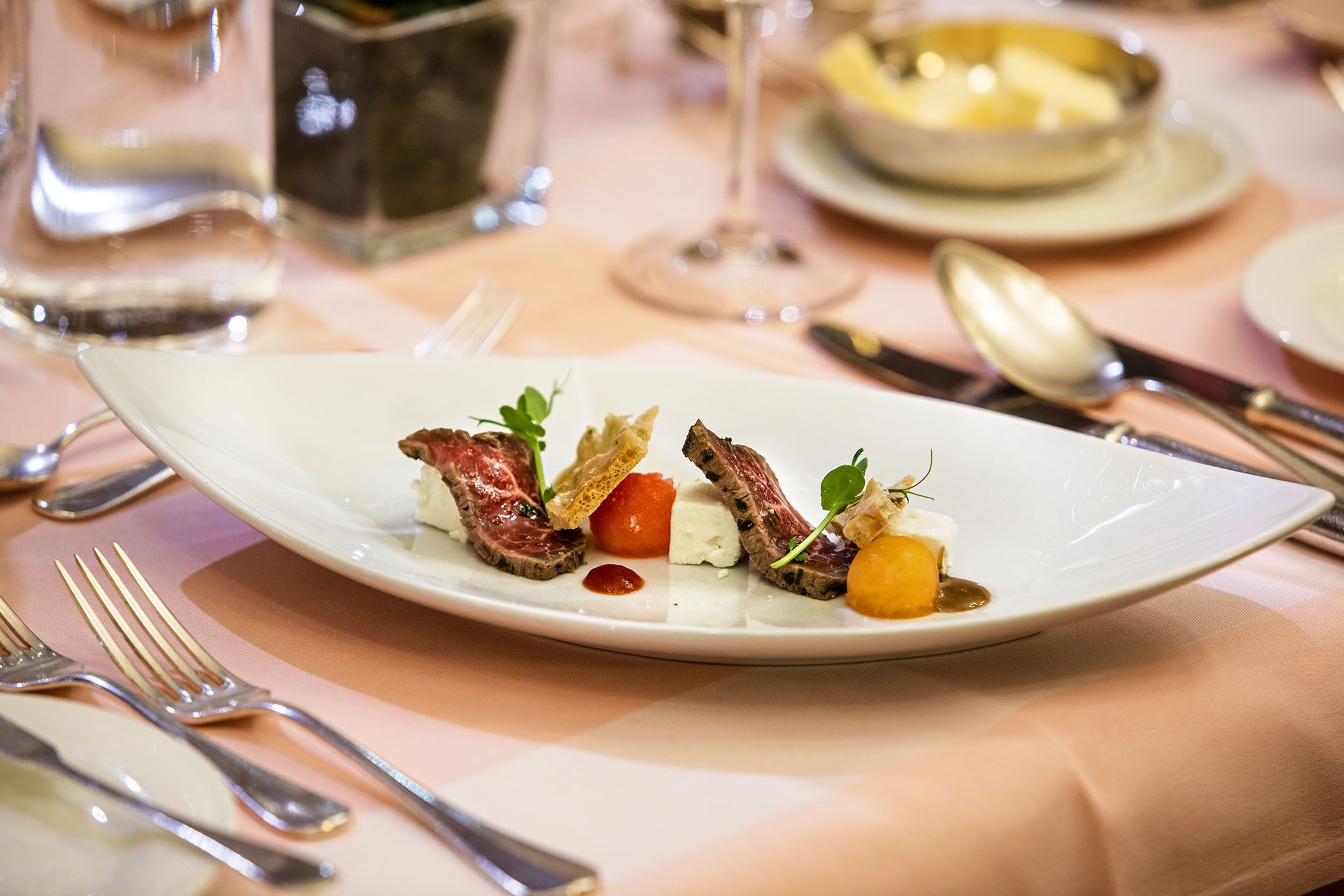 A white plate with food on a tablecloth.