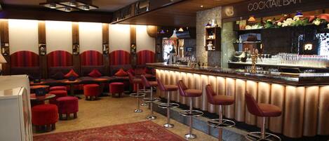 A cocktail bar with bar stools, a red carpet, and a patterned rug.