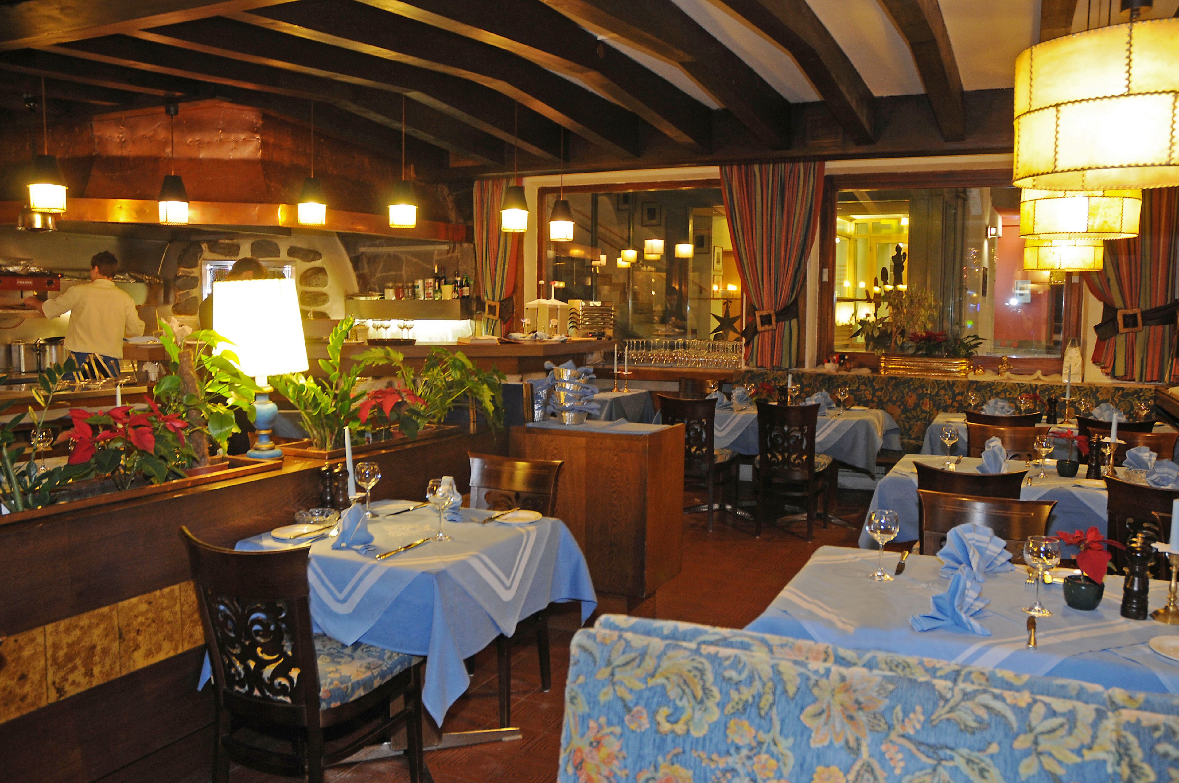 A restaurant with tables set for dining, a bar area, and a kitchen visible in the background.