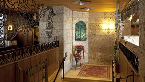 A staircase with ornate metal railings, a patterned rug, and a decorative wall with a green arch. - Sporthotel St. Anton (Sankt Anton am Arlberg)