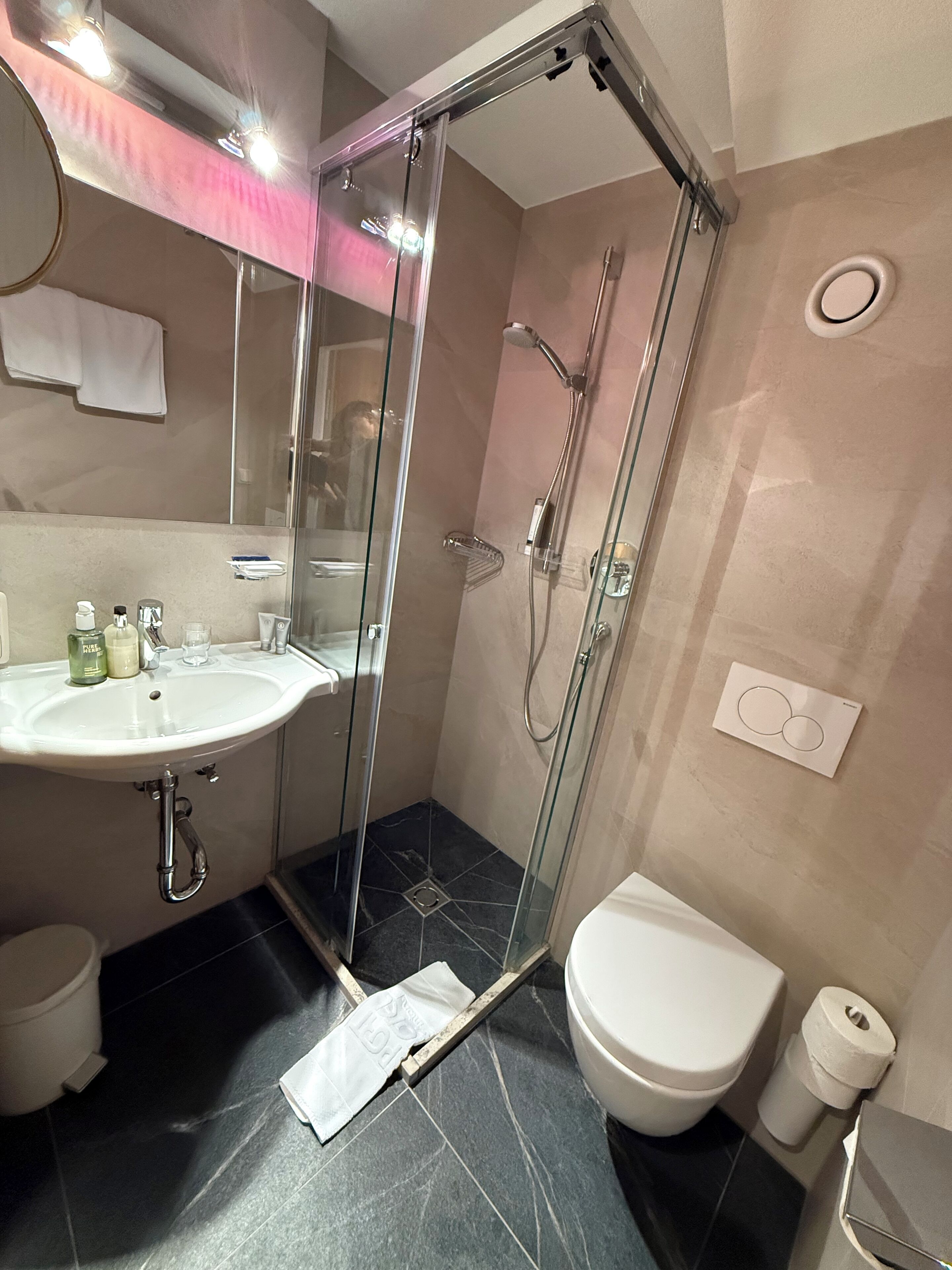 A modern bathroom with a glass-enclosed shower, a white sink, and a toilet.
