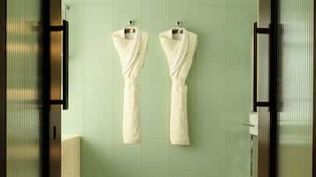 A hotel bathroom with two towels hanging on a wall, a patterned floor, and a ceiling light.