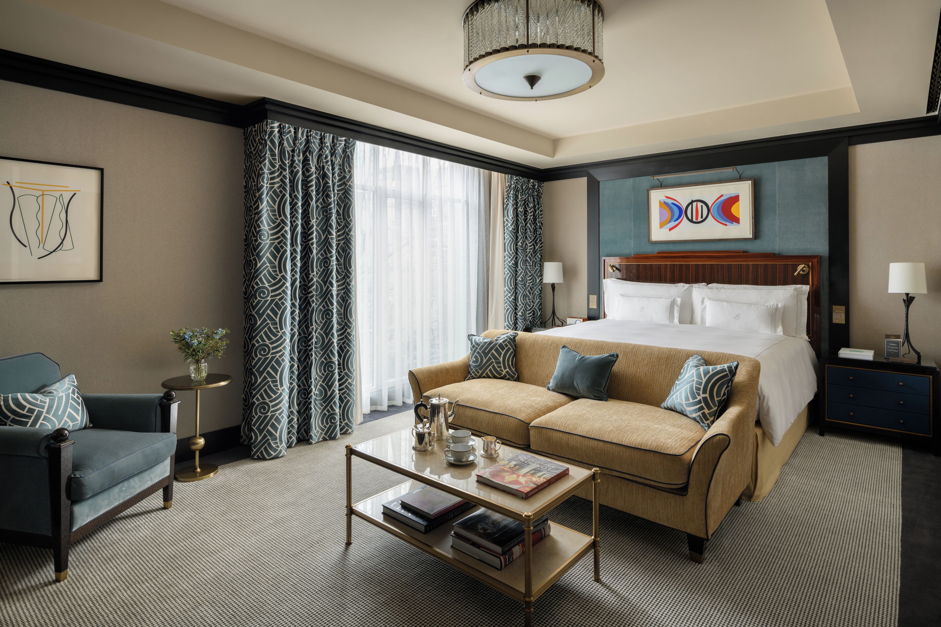 A hotel room with a bed, a sofa, a coffee table, and a desk with a lamp.