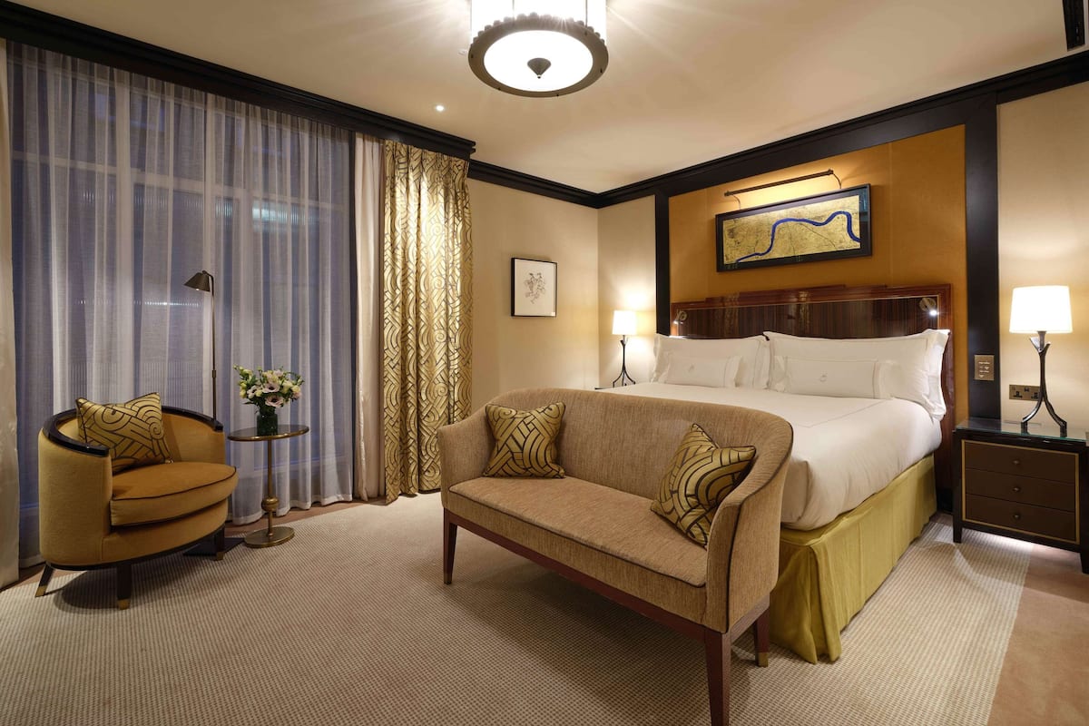 Ein Hotelzimmer mit einem großen Bett, einer Couch, einem kleinen Tisch mit einer Vase und einer Lampe.