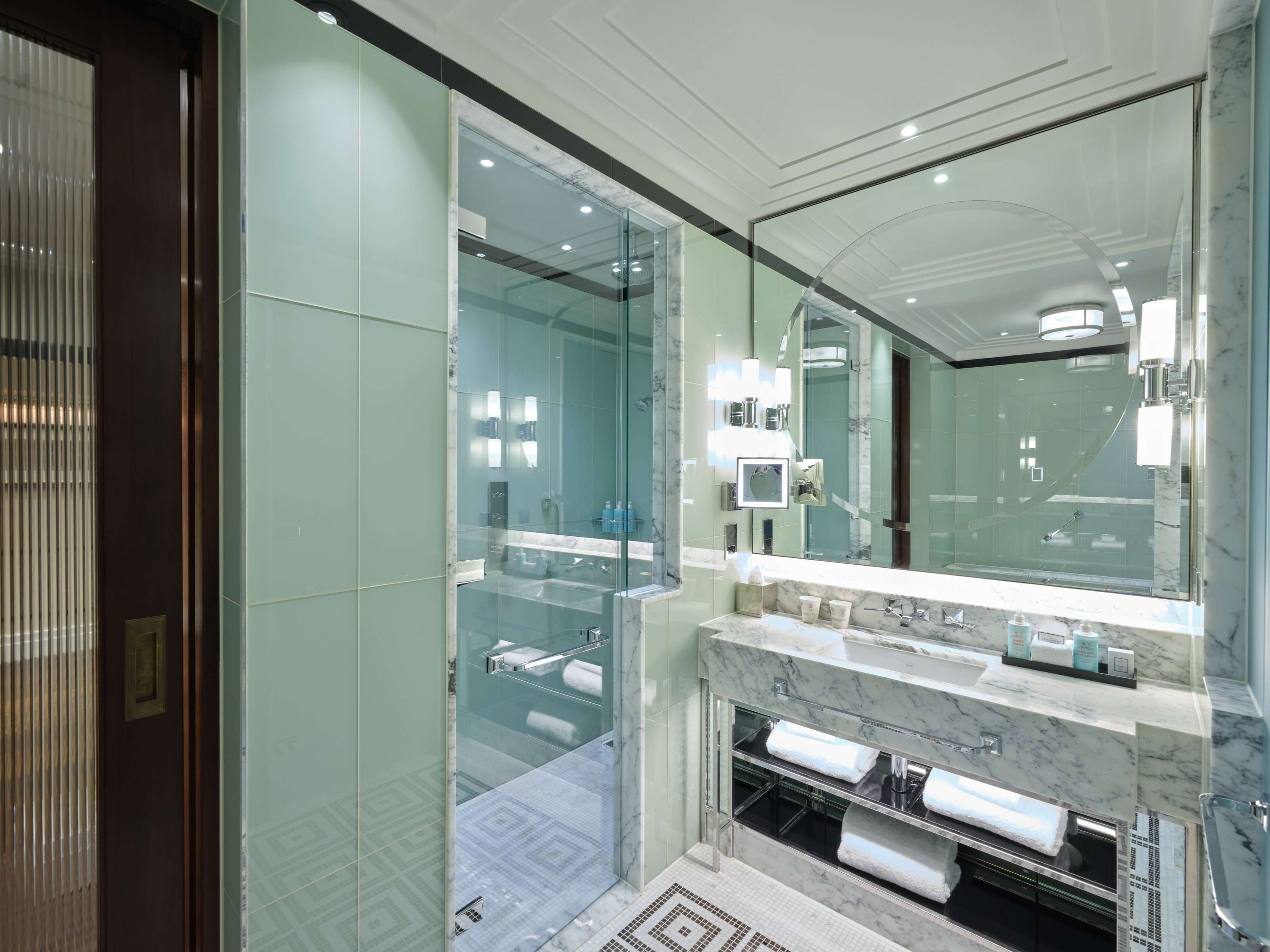 Une salle de bain moderne avec une douche à parois de verre, un grand miroir et un plan de toilette en marbre.