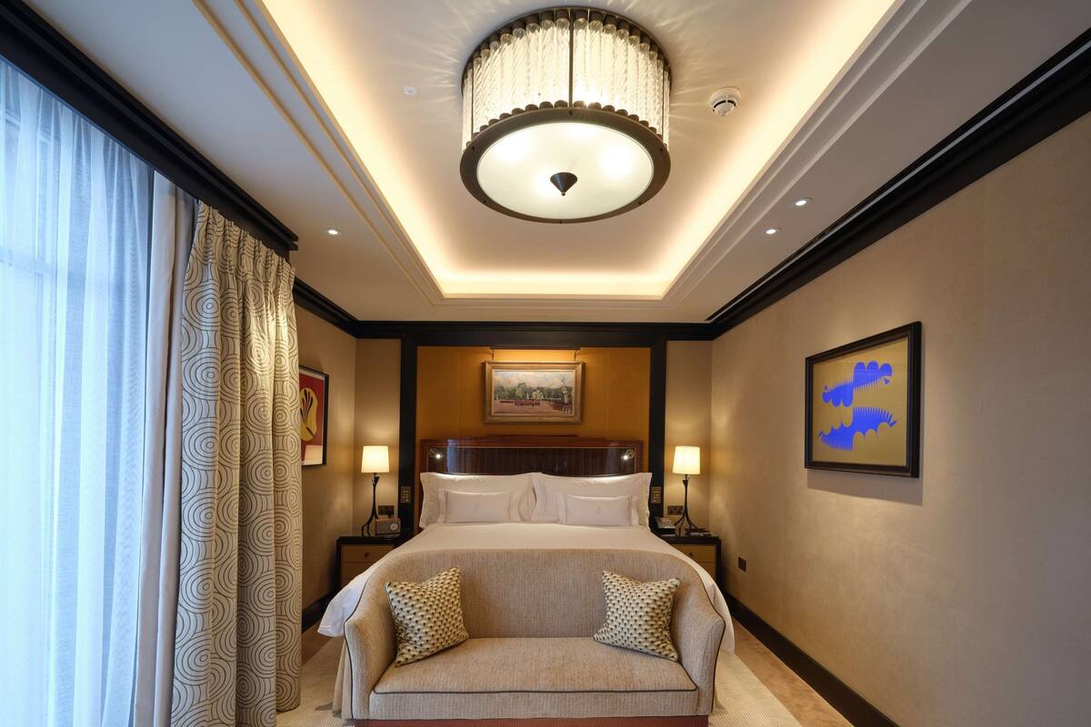 Ein Hotelzimmer mit einem großen Bett, einer Couch, zwei Nachttischen mit Lampen, einer Kristallleuchtre und einem Bild an der Wand.