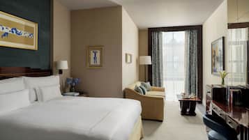 A hotel room with a large bed, a sofa, a desk, and a television.