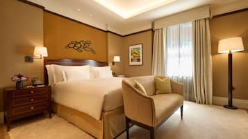 A hotel room with a large bed, a chair, a nightstand, and a lamp.
